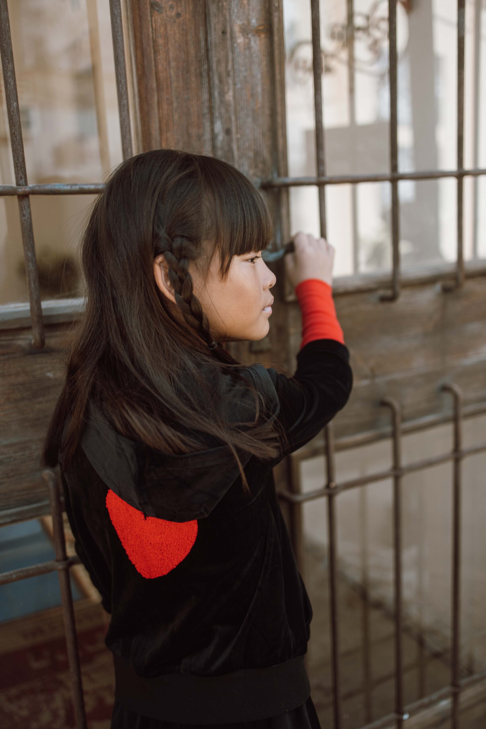 ילדה לובשת קפו׳צון קטיפה שחור עם חפת אדום ולב אדום בגב